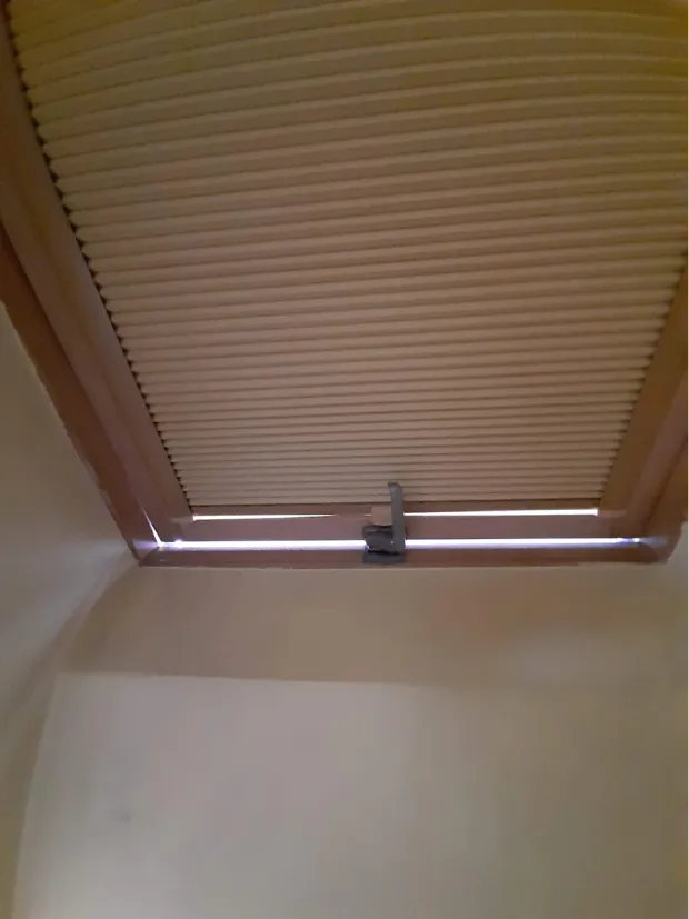 Plisa na oknie dachowym w skosie poddasza, tkanina dociśnięta prowadnicami do szyby